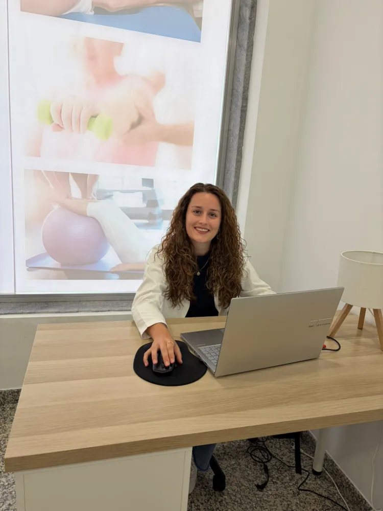 Fisioterapeuta na sala de tratamento com bola de pilates ao fundo