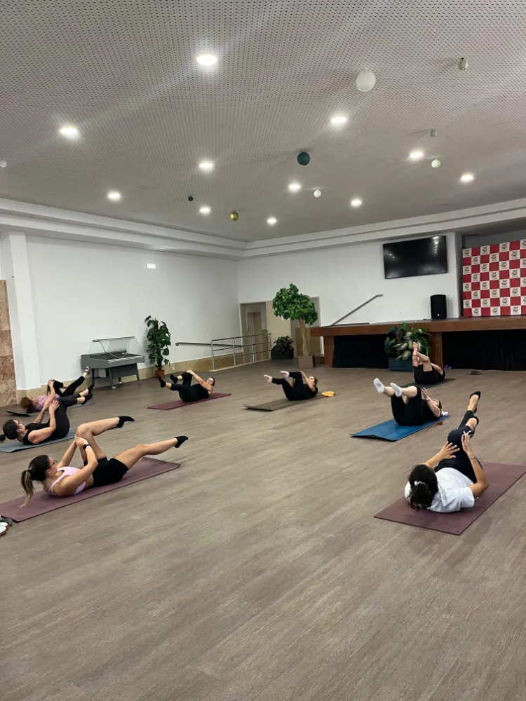 Utentes em exercício de pilates em colchões durante sessão de grupo